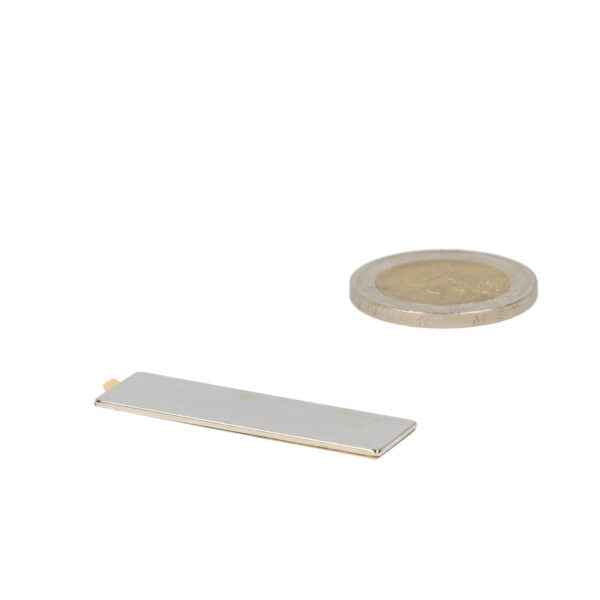 Zilverkleurige neodymium blokmagneet 40x12x1 mm naast munt voor schaal met krachtige magnetische oplossing
