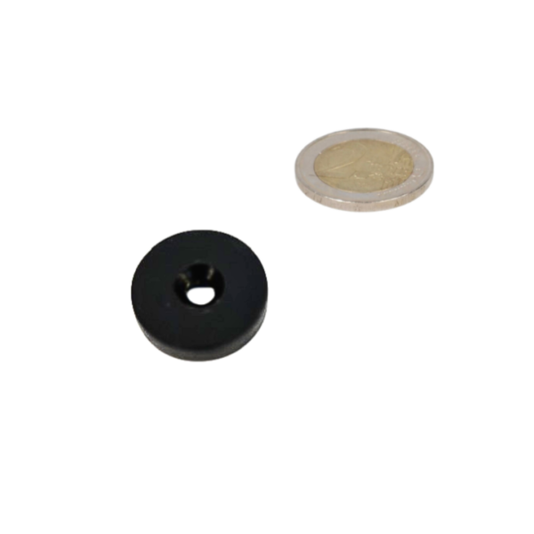Zwart ringmagneet 25,4 mm diameter met kunststof beschermlaag en verzinkgat naast zilveren munt voor schaal en magnetische kracht